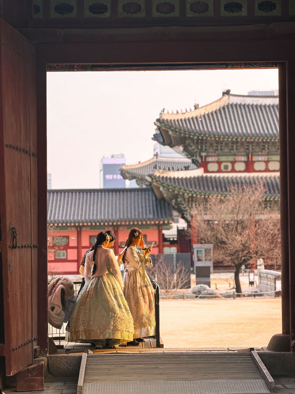 Two women in hanbok framed by a palace gate