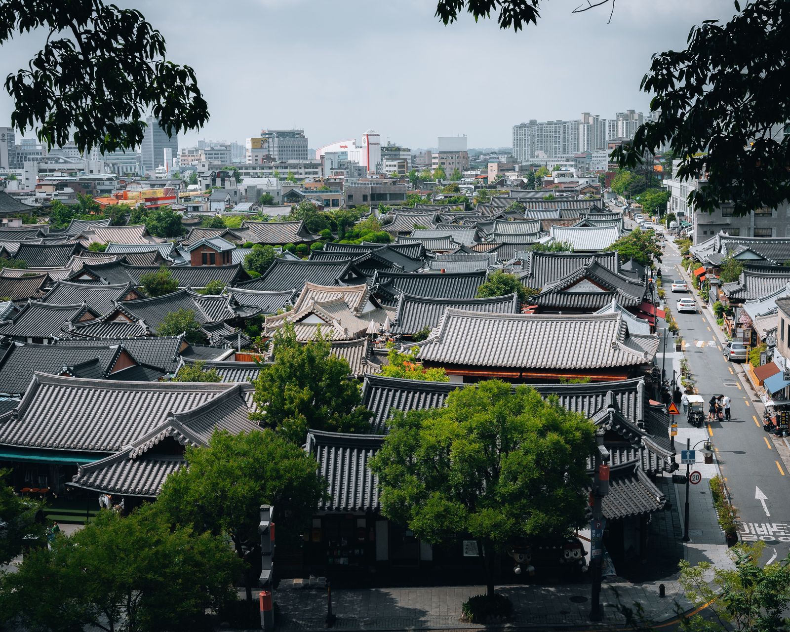 Tiled hanok rooftops of Jeonju Hanok Village seen from above, with the city behind