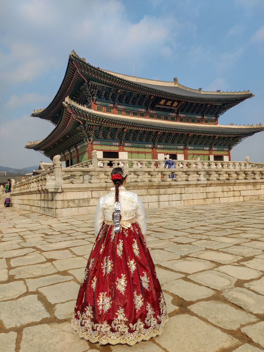 A woman in a red hanbok in a palace courtyard